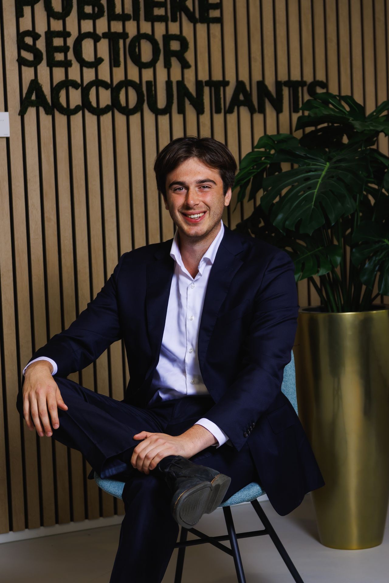 Collega van Publieke Sector Accountants die poseert voor het bedrijfslogo in een moderne kantooromgeving.