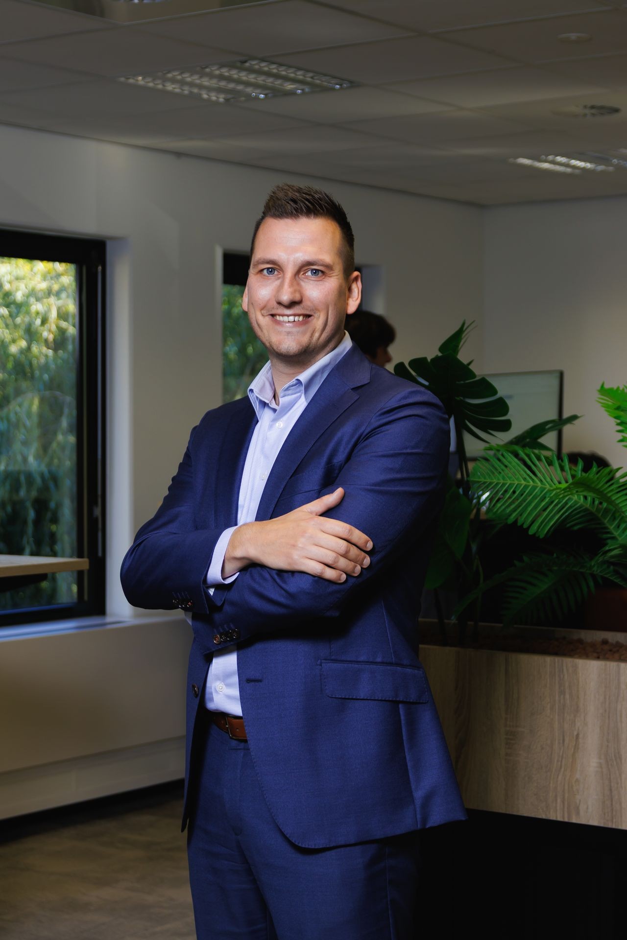 Collega bij Publieke Sector Accountants die poseert in een modern kantoor met planten en open werkruimtes.