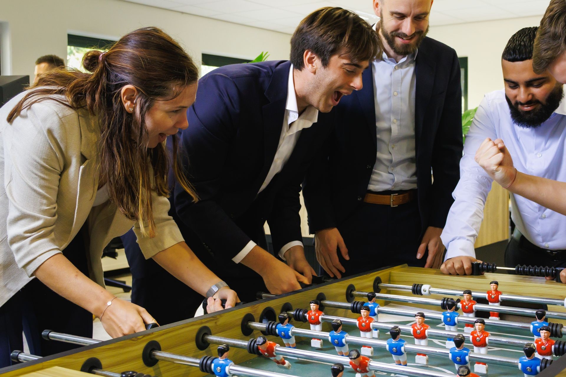 Collega’s van Publieke Sector Accountants spelen tafelvoetbal als onderdeel van een informele, mensgerichte werkomgeving binnen de publieke auditsector.