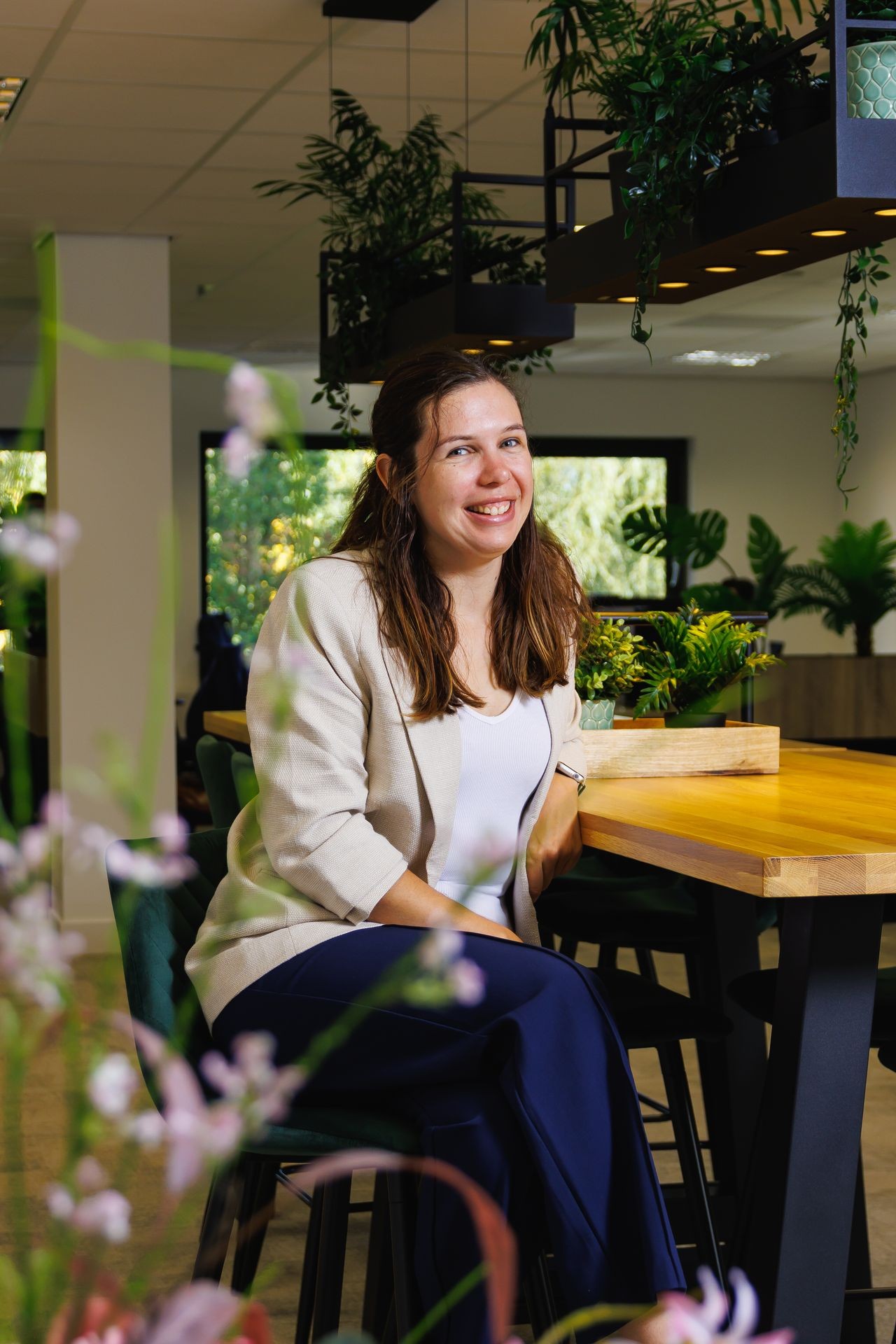 Collega van Publieke Sector Accountants die poseert aan een hoge tafel in een groene en open kantoorruimte.