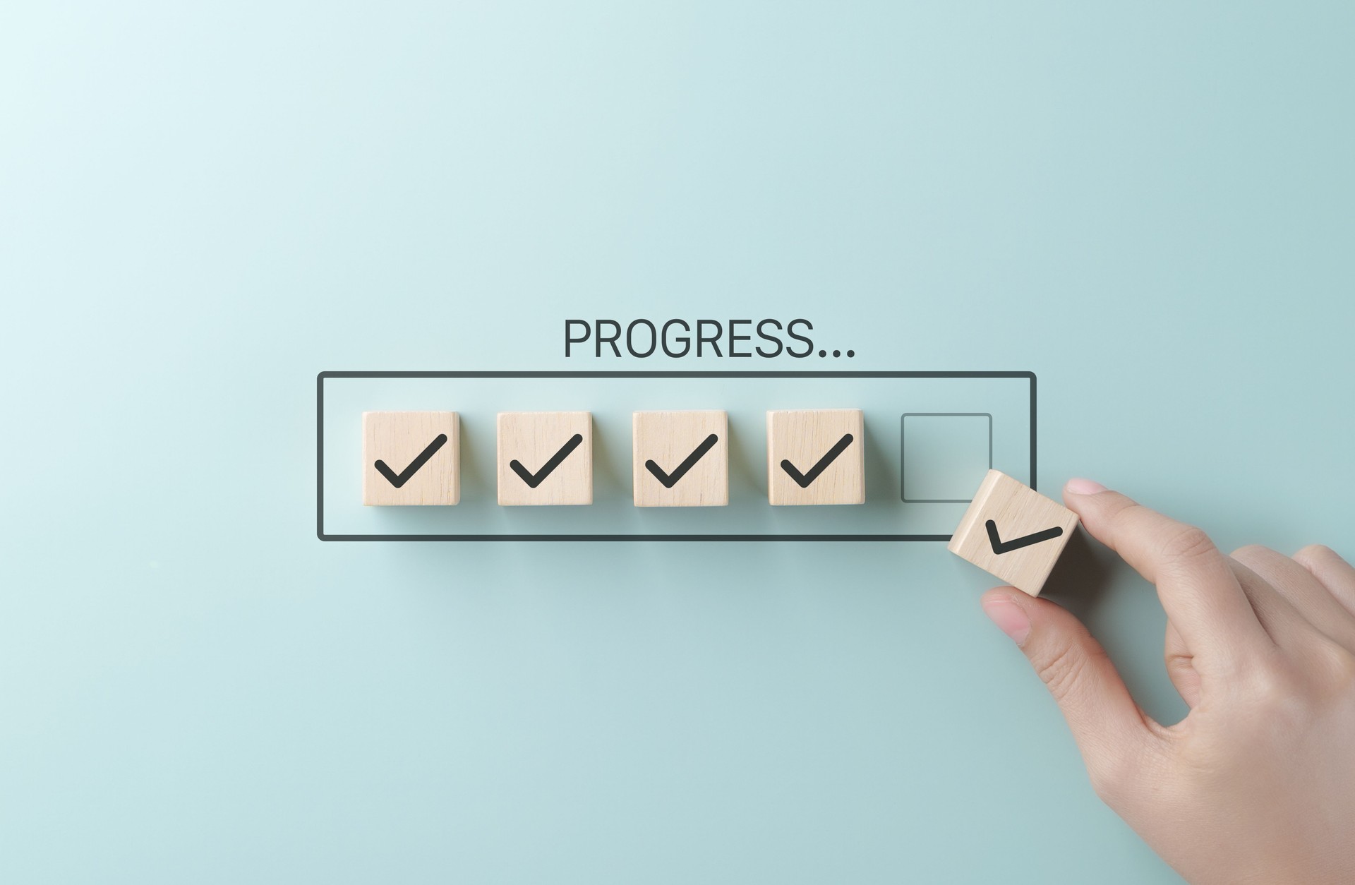 Hand die een laatste checklist-blokje plaatst in een voortgangsbalk.